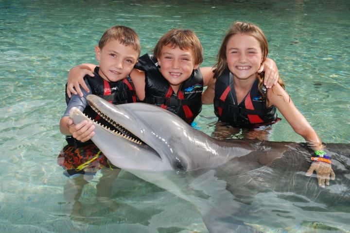 Three little kids wearing wetsuit having a dolphin tour experience.