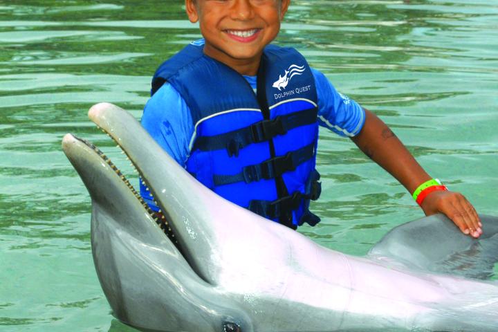 A little kid wearing wetsuit having a dolphin tour experience.