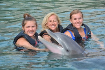 A family wearing wetsuits having dolphin experience in the pool.