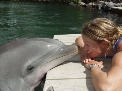 A woman and a dolphin facing each other.