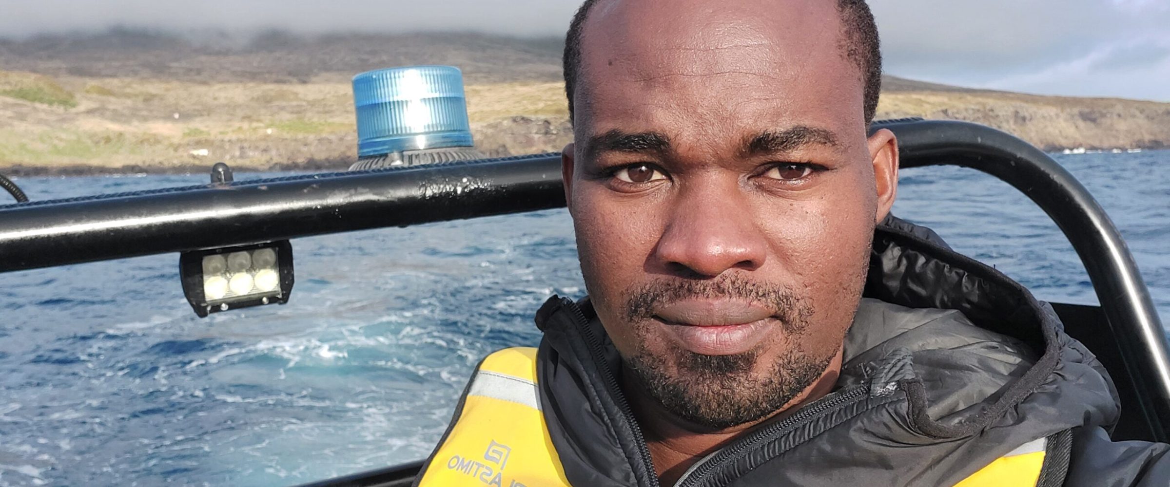 Closed up photo of Michael Mwangombe wearing wetsuits on the boat. Closed up photo of Michael Mwangombe wearing wetsuits on the boat.