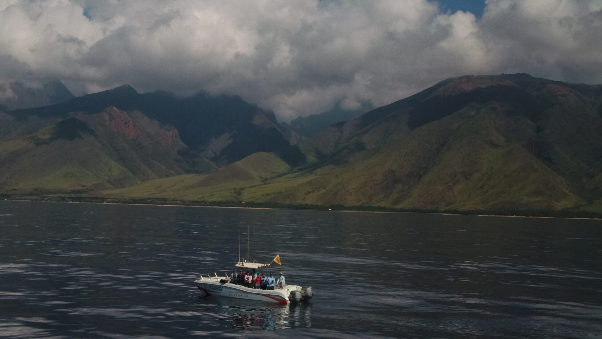 A boat sailing on the ocean with majestic mountains in the background. A boat sailing on the ocean with majestic mountains in the background.