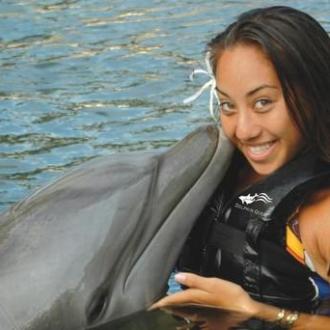 A women receiving a kiss from a dolphin
